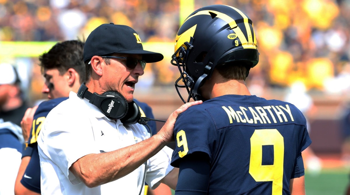 Michigan football coach Jim Harbaugh pumps up quarterback J.J. McCarthy on the sidelines